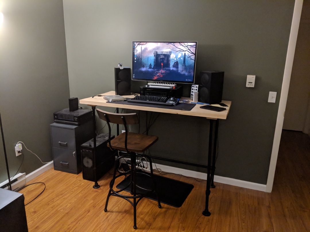 A standing height desk with a monitor and speakers on it