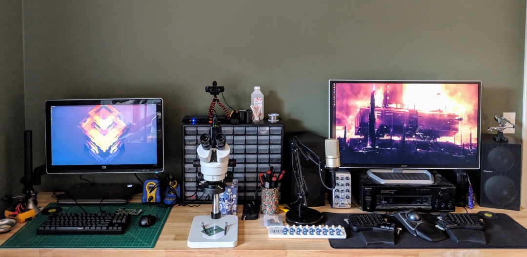 A workbench with two computer monitors and a microscope