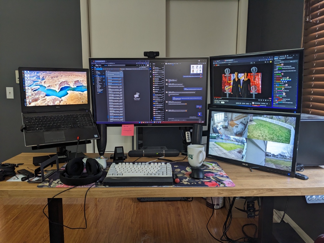 A desk with three monitors and a laptop on it