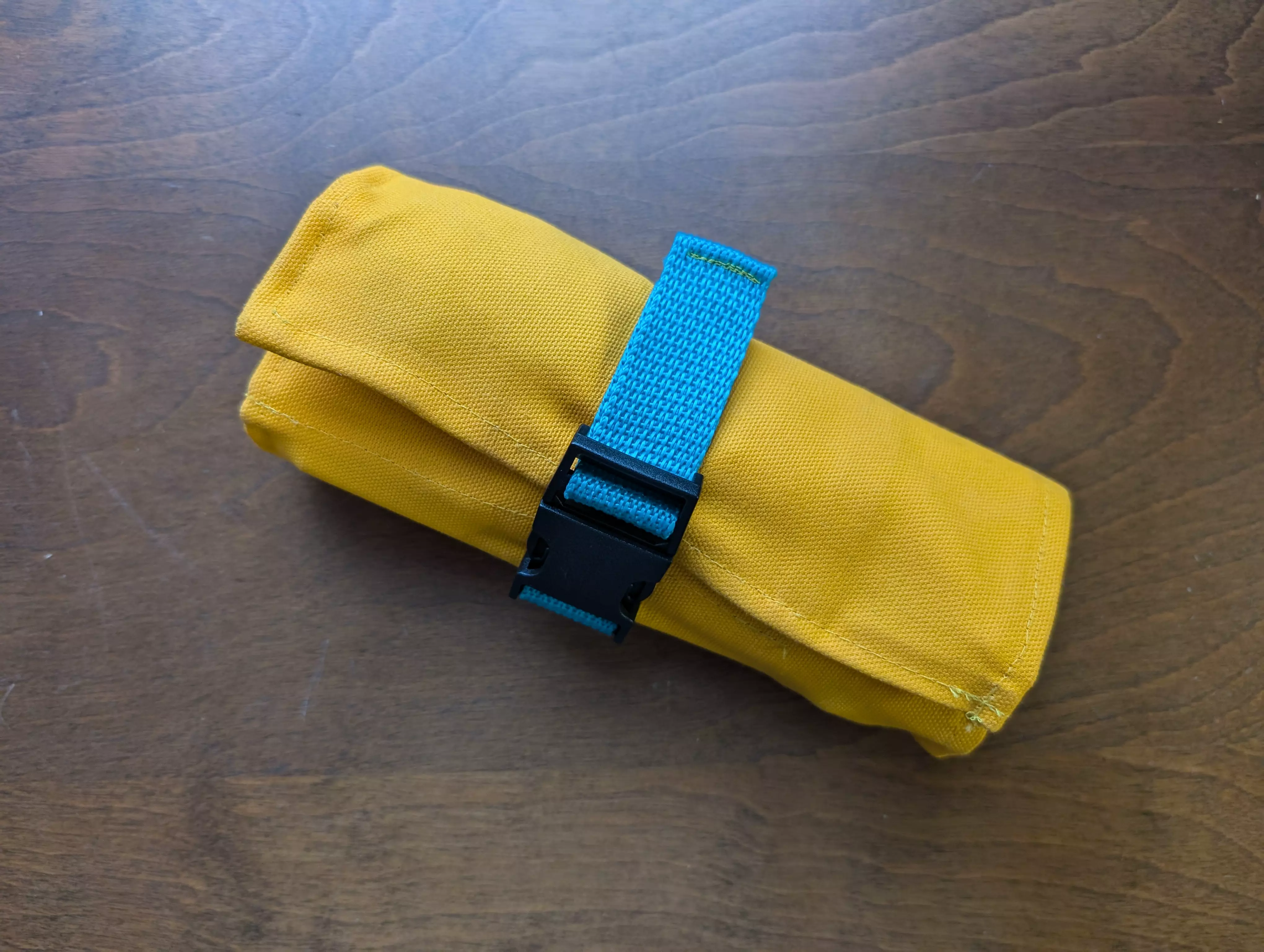 A photo of a yellow and blue tool roll rolled up on a wooden table