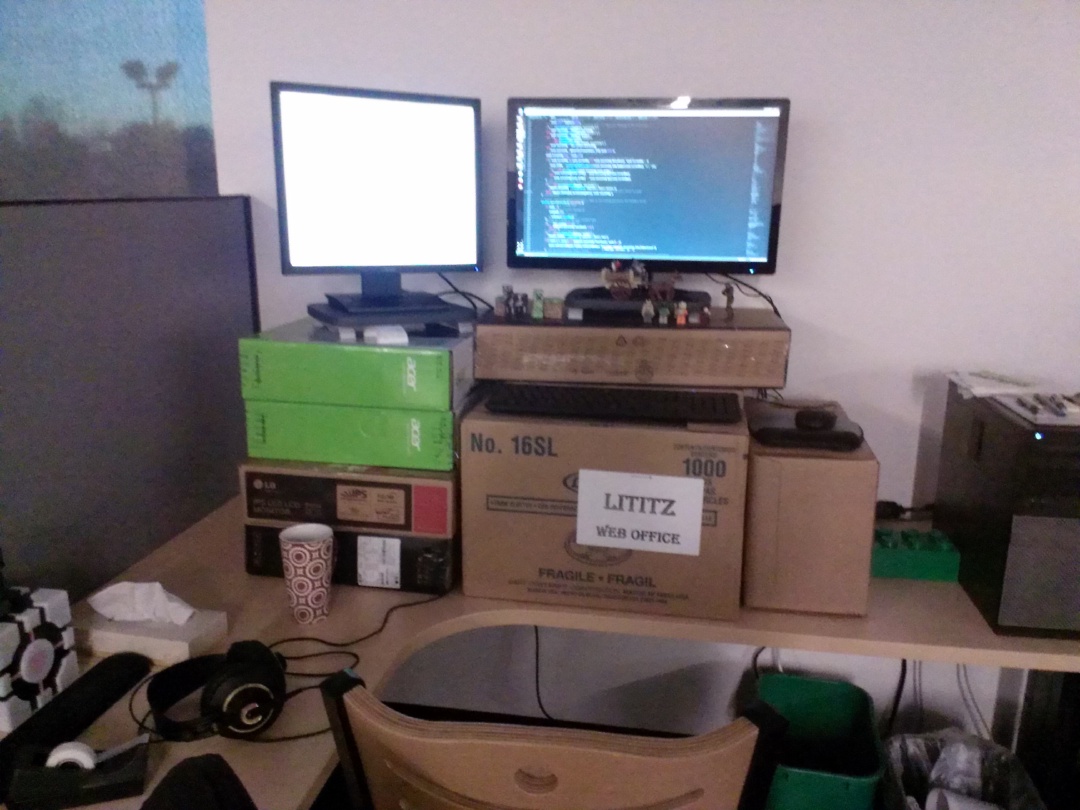 Two monitors on top of a pile of cardboard boxes